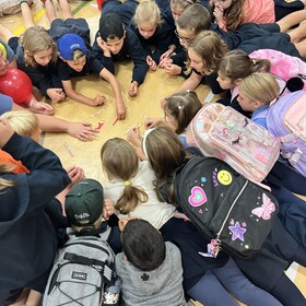 élèves sur le sol avec leur sac à dos jouant à un jeu
